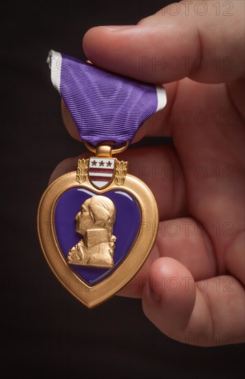 Male hand holding the United States armed forces purple heart medal