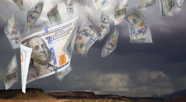 Several 100 dollar bills falling from stormy cloudy sky