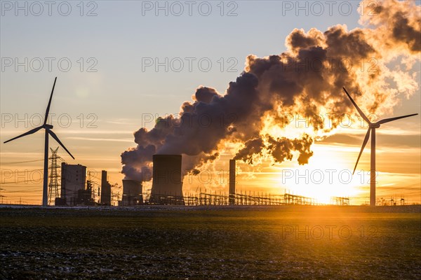 Wind turbines in front of steaming coal-fired power plant at sunset