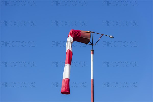 Red and white windsock against blue sky