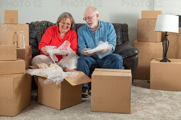 Senior adult couple packing or unpacking moving boxes