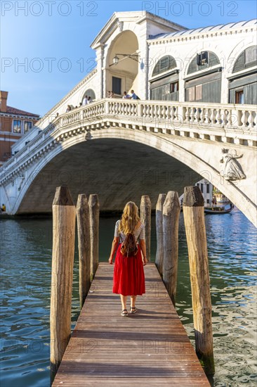 Young woman with red dress at a pier with boats