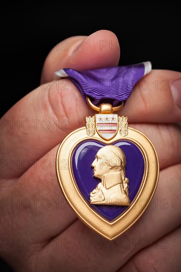 Male hand holding the United States armed forces purple heart medal