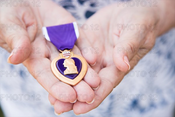 Senior woman holding the United States military purple heart medal in her hands