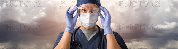 Doctor or nurse adjusting safety goggles wearing personal protective equipment over ominous clouds