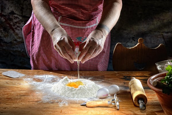 Cook making pasta dough on wooden table