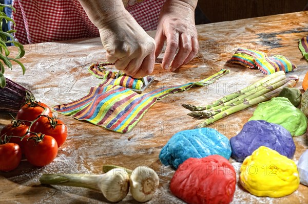 Cook cutting out fresh colorful ravioli with ravioli cutter