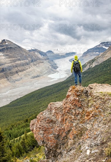 Hiker standing on rocks overlooking valley with glacier tongue