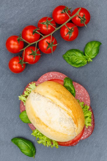 Roll sandwich baguette topped with salami ham from above slate plate