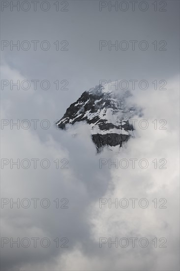 Snow covered mountain peaks in clouds