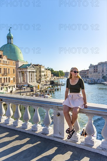 Young woman sitting on bridge railing on the Grand Canal