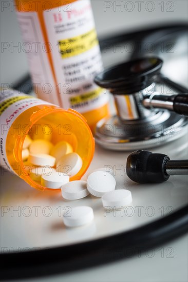 Non-Proprietary medicine prescription bottles and spilled pills abstract with stethoscope