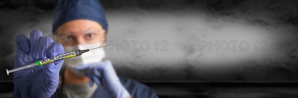 Doctor or nurse wearing surgical glove holding medical syringe with coronavirus COVID-19 vaccine label banner