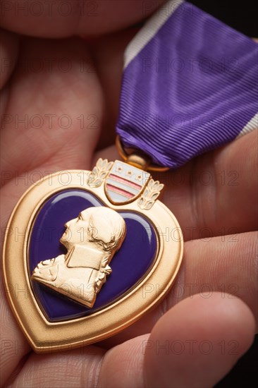 Male hand holding the United States armed forces purple heart medal