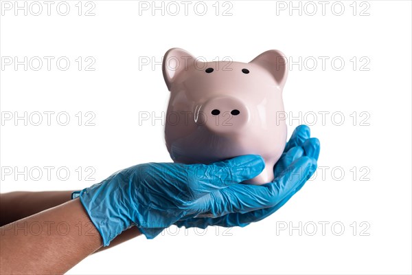 Doctor or nurse wearing surgical gloves holding piggy bank isolated on white