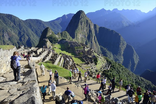 Tourists in the ruined city of the Incas with Mount Huayna Picchu