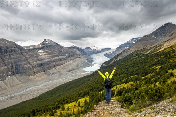 Hiker standing on rocks overlooking valley with glacier tongue