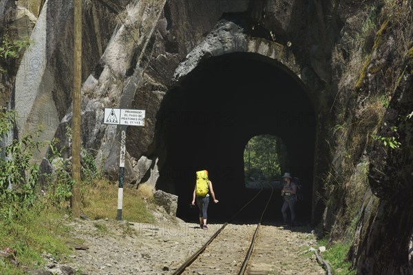 Tourists with backpack in the tunnel of the railway to Cusco