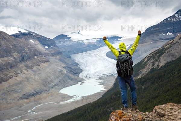 Hiker standing on rocks overlooking valley with glacier tongue