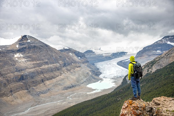 Hiker standing on rocks overlooking valley with glacier tongue