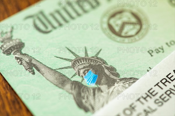 United states IRS stimulus check with statue of liberty wearing medical face mask