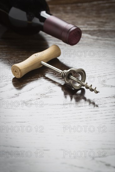 Abstract wine bottle and corkscrew laying on a reflective wood surface with room for text