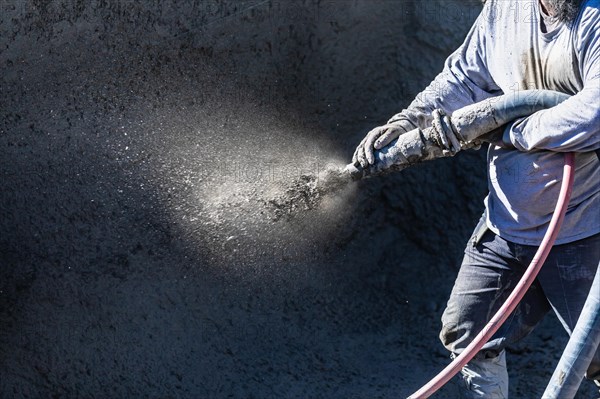 Pool construction worker shooting concrete