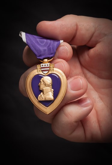 Male hand holding the United States armed forces purple heart medal