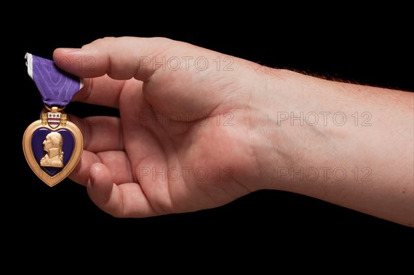 Man holding United States purple heart war medal on a black background