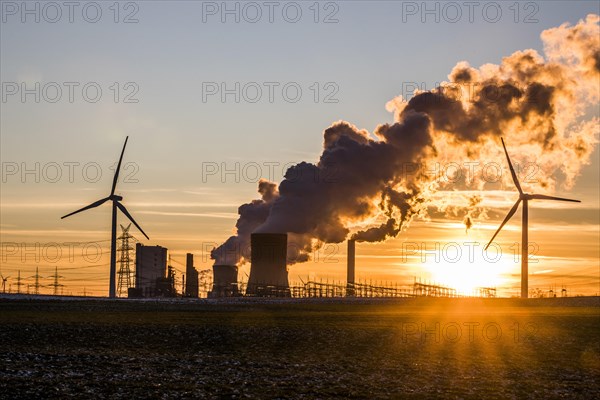 Wind turbines in front of steaming coal-fired power plant at sunset