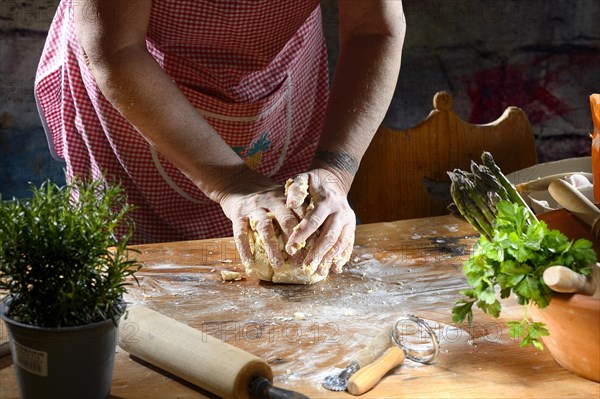 Cook kneading pasta dough for pasta on wooden table