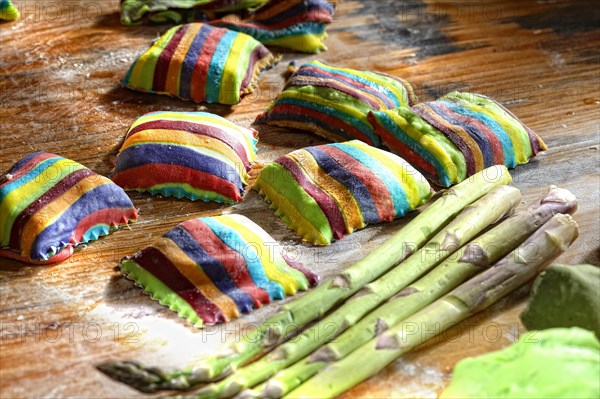 Homemade colorful ravioli on floured wooden table