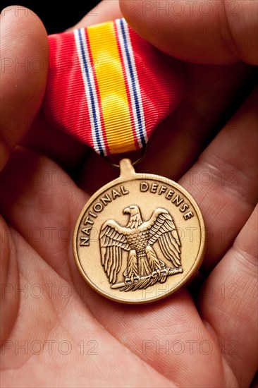 Man holding national defense war medal in the palm of his hand