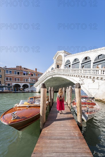 Young woman with red dress at a pier with boats