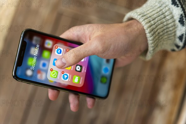 Hand haelt iPhone 11 Pro mit App-Icons von Messenger Diensten und Sozialen Netzwerken