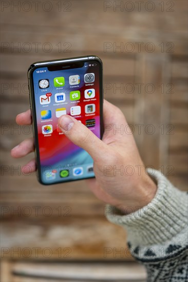 Hand haelt iPhone 11 Pro mit Homescreen