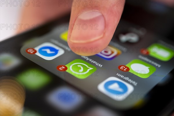 Finger tapping on screen with app icons of messenger services and social networks