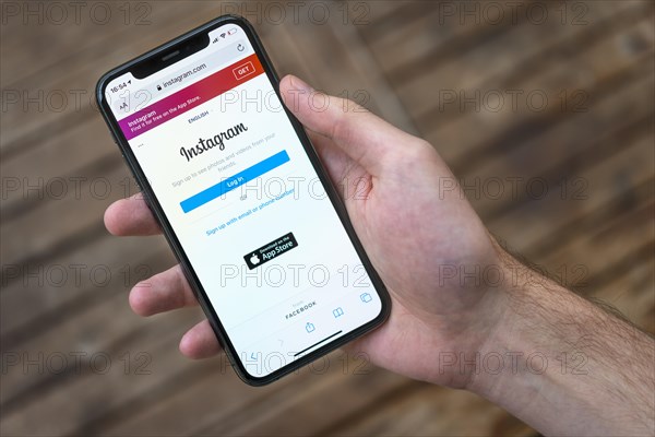 Hand haelt iPhone 11 Pro mit geoeffneter Instagram Website