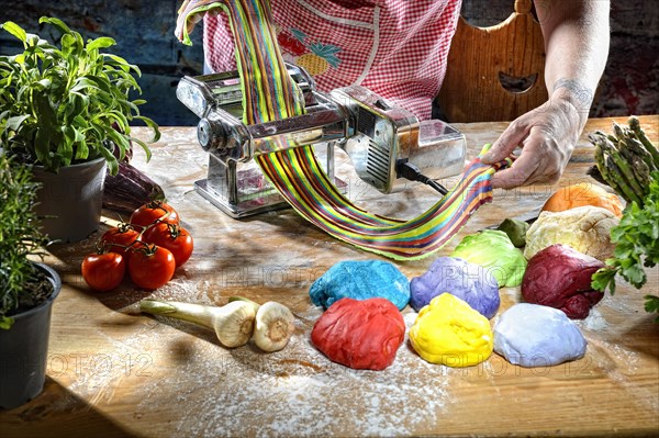 Cook with pasta machine making coloured pasta dough