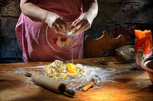 Woman beats egg on flour for pasta dough