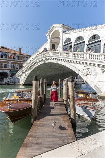 Young woman with red dress at a pier with boats