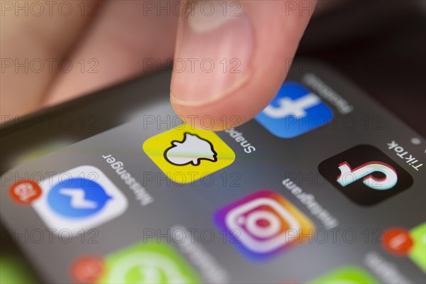 Finger tapping on screen with app icons of messenger services and social networks
