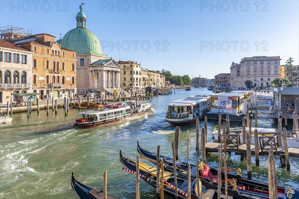 Gondolas and boats on the Grand Canal with church San Simeone Piccolo at the Ponte degli Scalzi