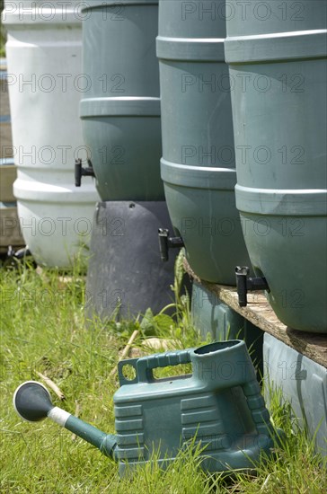 Plastic waterbutts and watering can on village allotment plot