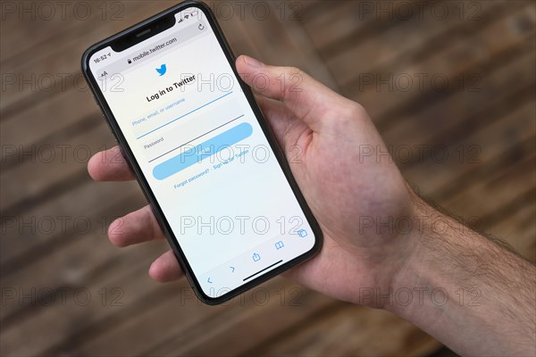 Hand haelt iPhone 11 Pro mit geoeffneter Twitter Website