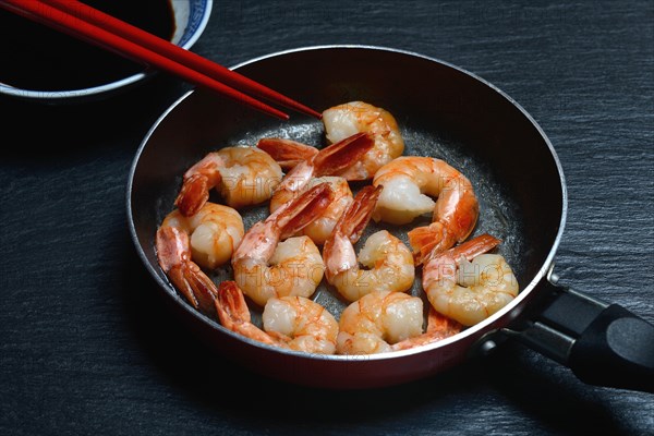 Fried prawns in pan and small bowl with soy sauce