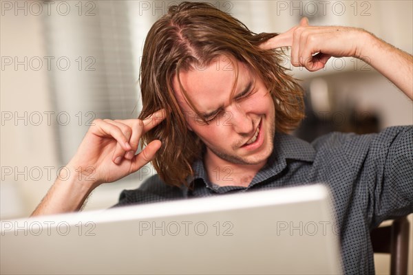Young man getting loopy while using his laptop computer