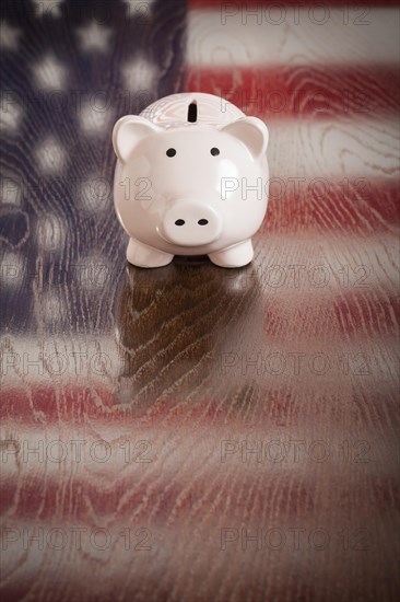 Piggy bank with an american flag reflection on wooden table