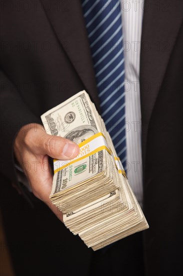 Businessman handing over stack of one hundred dollar bills