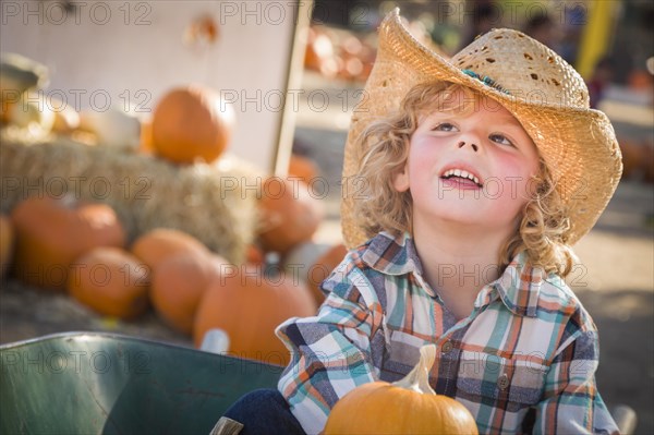 Adorable little boy wearing cowboy hat at pumpkin patch farm